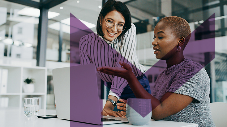 Two happy women looking at laptop in the office