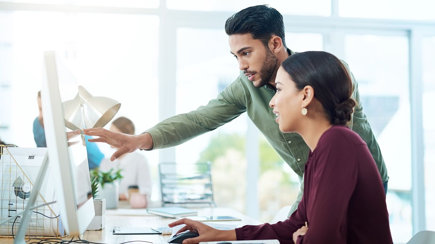 two people in the office looking at a monitor