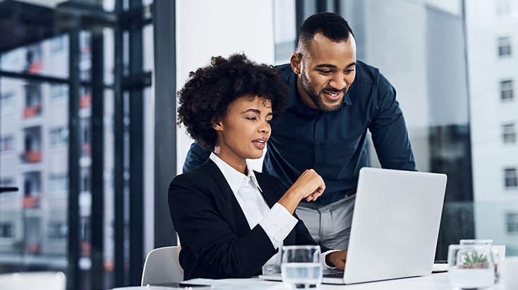 two people looking at a laptop in the office