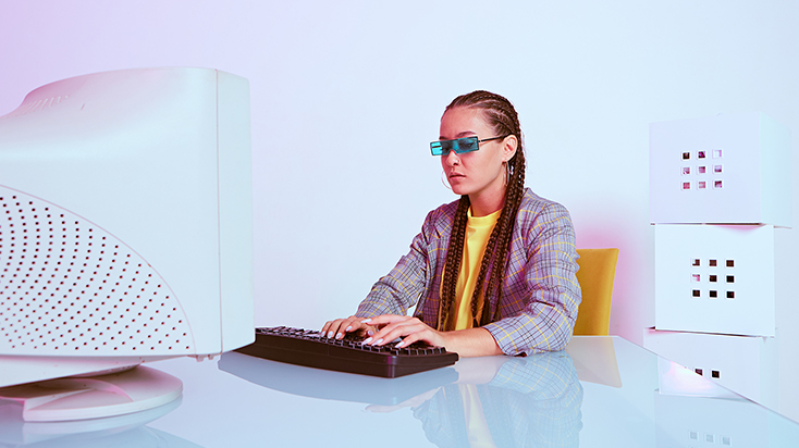 Woman at an old computer dressed in an outfit from the 90's