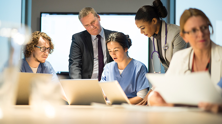 Group of colleagues reviewing work on laptop