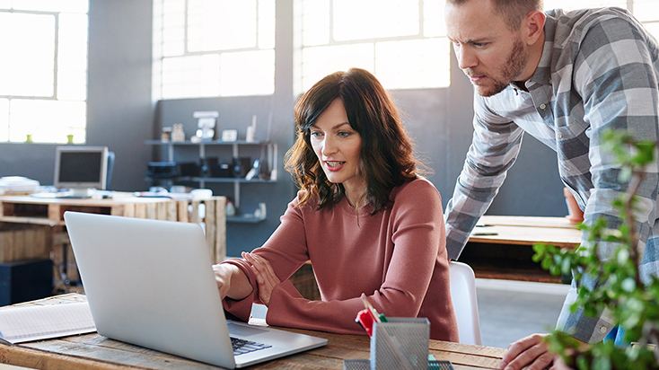 man and woman looking at laptop in the office