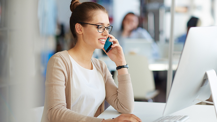 Professional woman using laptop and cell phone