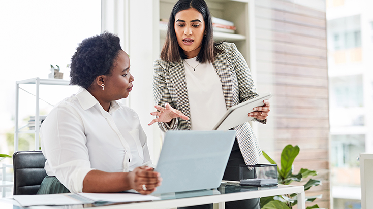 Two professional women working on a laptop