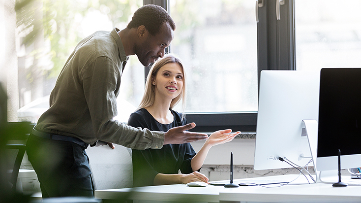 Two coworkers looking at laptop