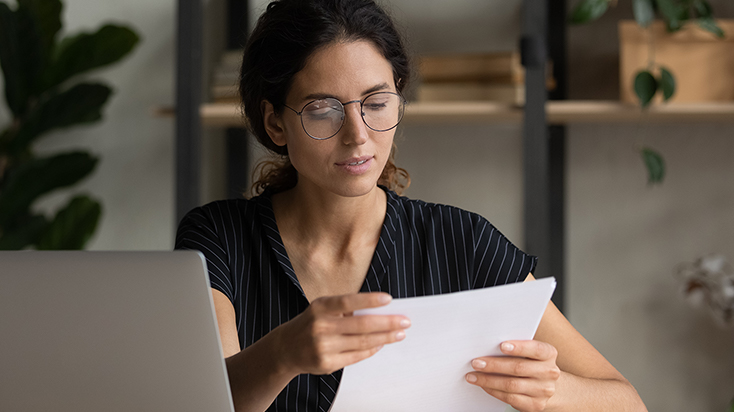 Young woman reading mail at her desk