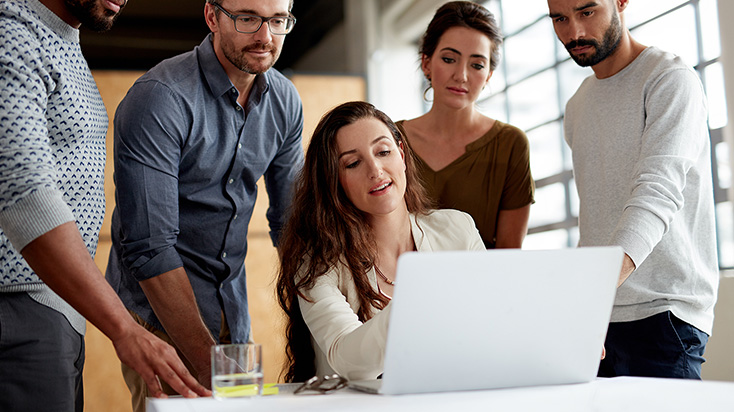 Coworkers gathered around a laptop