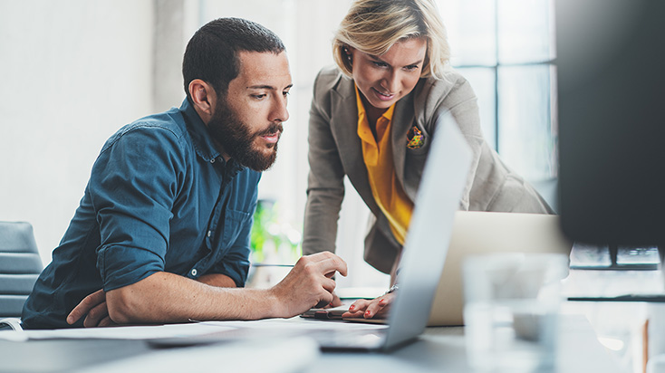 Two coworkers looking at a laptop