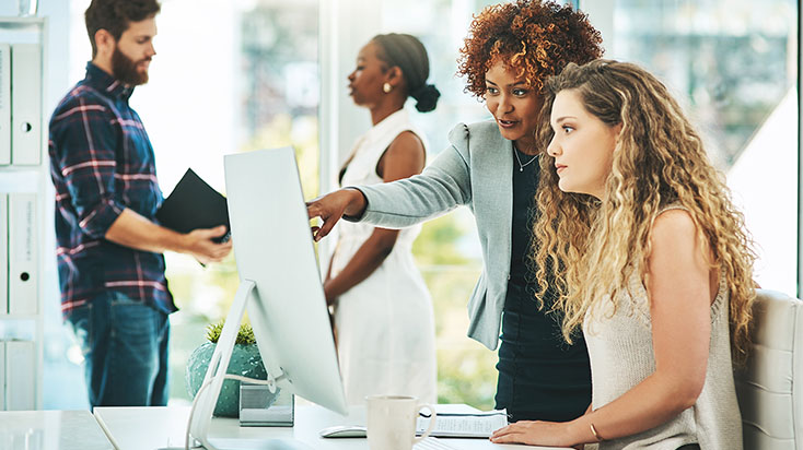 Two business women woking together on a computer