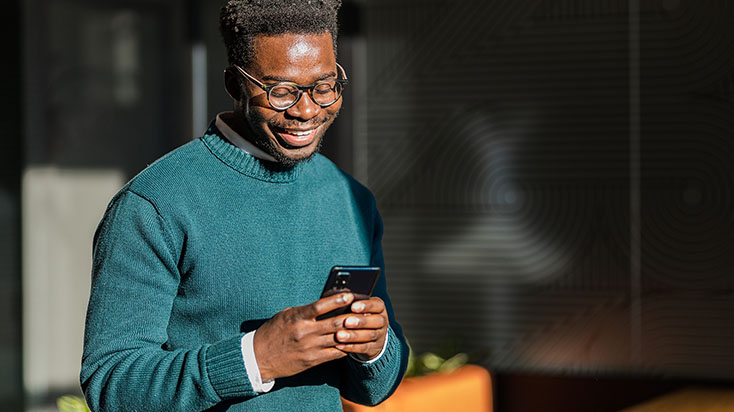 Young man happily looking at his phone